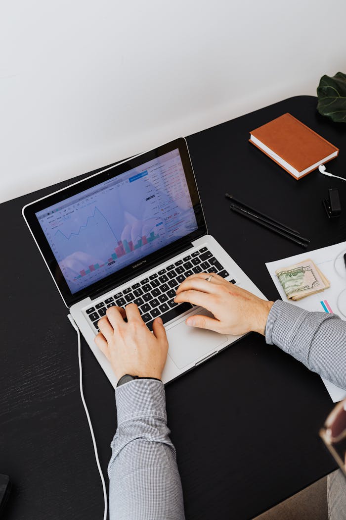 why-choose-us Hands typing on a laptop showing graphs on screen, analyzing financial data.